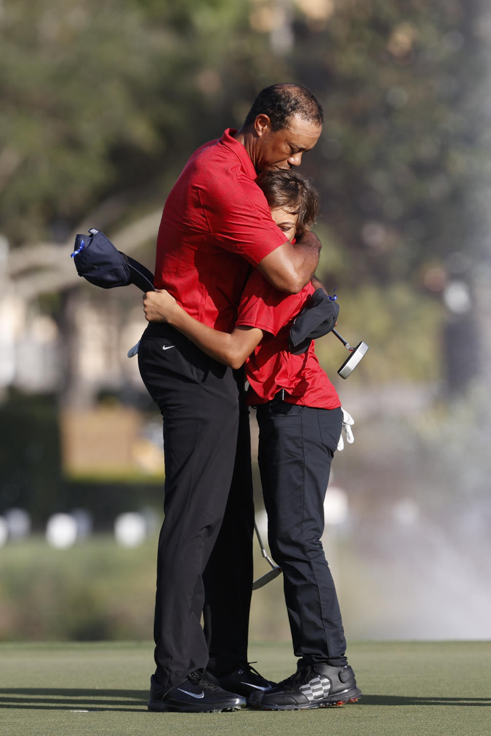 Tiger Woods hugs son Charlie Woods on the 18th green after the second round of the PNC Championship golf tournament, Sunday, Dec. 19, 2021, in Orlando, Fla. (AP Photo/Scott Audette)