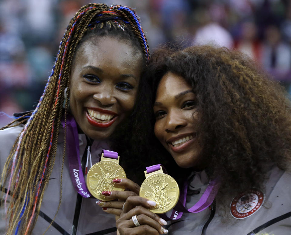 File-This Aug. 5, 2012, file photo shows Venus Williams, left, and Serena Williams of the United States showing their gold medals in women's doubles at the All England Lawn Tennis Club in Wimbledon, London at the 2012 Summer Olympics. Williams has been voted the AP Female Athlete of the Decade for 2010 to 2019. Williams won 12 of her professional-era record 23 Grand Slam singles titles over the past 10 years. No other woman won more than three in that span. She also tied a record for most consecutive weeks ranked No. 1 and collected a tour-leading 37 titles in all during the decade. Gymnast Simone Biles finished second in the vote by AP member sports editors and AP beat writers. Swimmer Katie Ledecky was third, followed by ski racers Lindsey Vonn and Mikaela Shiffrin. (AP Photo/Elise Amendola, File)