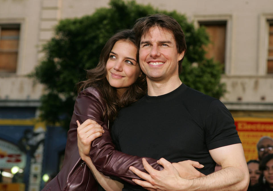 Katie Holmes and Tom Cruise pose closely outdoors, smiling while embracing