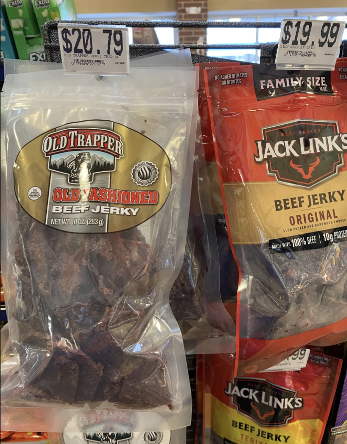 Two brands of beef jerky displayed on a store shelf with price tags visible both priced around $20 per bag