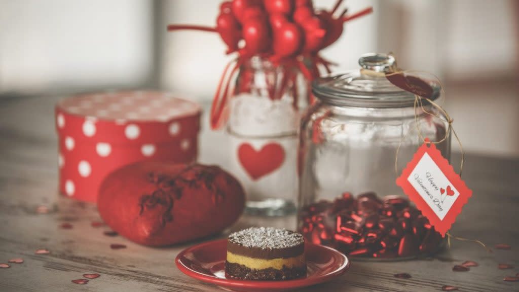 Front view of still life set of romantic red decorations and vegan cake for Valentine's celebration