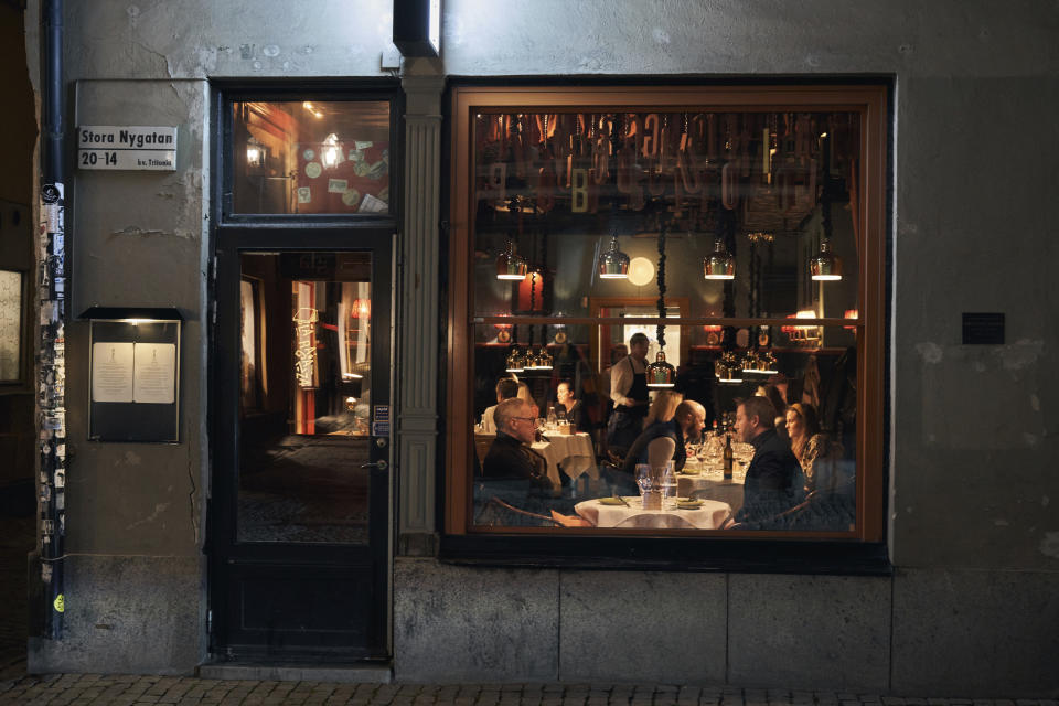 People sit in a restaurant in Stockholm, Wednesday, March 25, 2020. The streets of Sweden's capital are quiet but not deserted. Sweden has some of the most relaxed measures in Europe in the fight against the coronavirus outbreak. So far, only gatherings of over 500 people are banned and elementary and middle schools remain open. The new coronavirus causes mild or moderate symptoms for most people, but for some, especially older adults and people with existing health problems, it can cause more severe illness or death. (AP Photo/David Keyton)