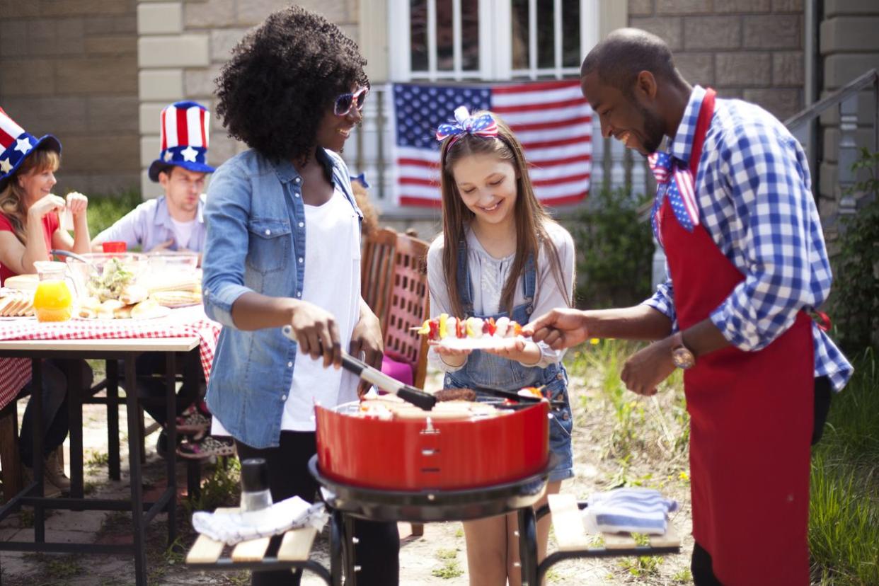 Man and Woman barbecuing and giving shish kebab to girl