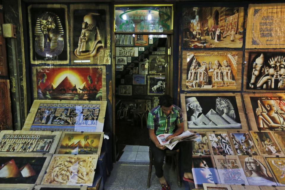 An Egyptian vendor reads a newspaper as he waits for customers in the Khan El-Khalili market, normally a popular tourist destination, in Cairo, Egypt, Monday, Sept. 9, 2013. Before the 2011 revolution that started Egypt's political roller coaster, sites like the pyramids were often overcrowded with visitors and vendors, but after a summer of coup, protests and massacres, most tourist attractions are virtually deserted to the point of being serene. (AP Photo/Lefteris Pitarakis)