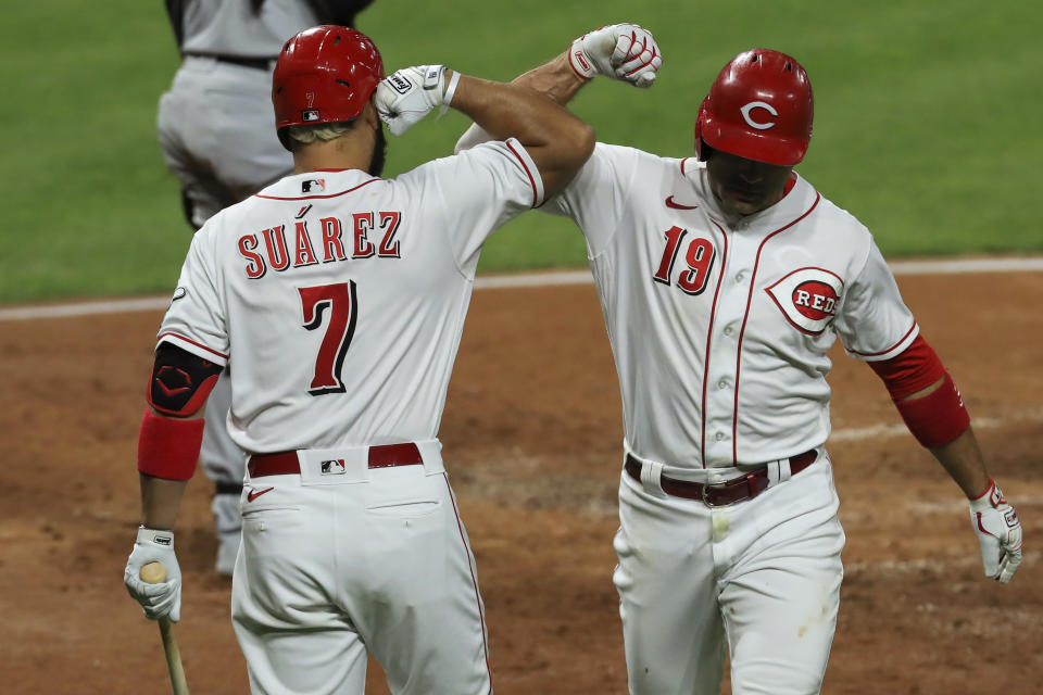 Cincinnati Reds' Eugenio Suarez, left, congratulates Joey Votto, who hit a solo home run during the third inning of the team's baseball game against the Chicago White Sox in Cincinnati, Friday, Sept. 18, 2020. (AP Photo/Aaron Doster)