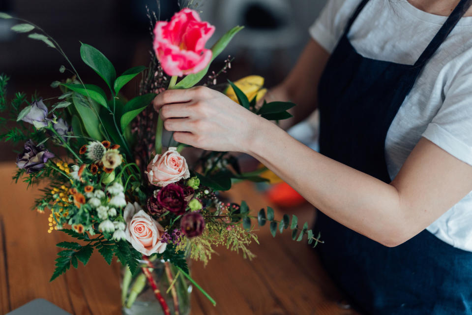 A woman arranging flowers in a vase.