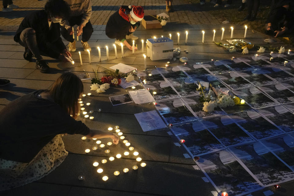 University students light candles at the site after the "Goddess of Democracy" statue, a memorial for those killed in the 1989 Tiananmen crackdown, was removed from the Chinese University of Hong Kong, Friday, Dec. 24, 2021. The university early Friday morning took down the statue that was based on a figure created by art students and brought to the square shortly before the crackdown in which hundreds of people were killed. (AP Photo/Vincent Yu)