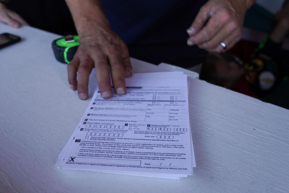 Don Caple shows a stack of voter registration forms at his roadside Trump-themed trailer in Amarillo.