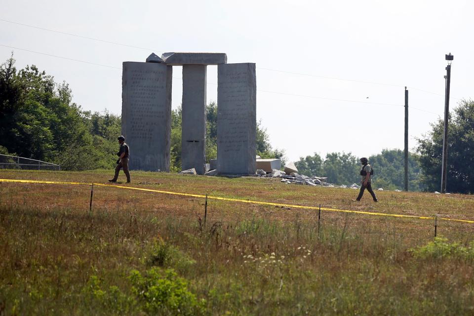 Law enforcement officials walk around the damaged Georgia Guidestones monument near Elberton, Georgia, on Wednesday, July 6, 2022. The Georgia Bureau of Investigation said the monument, which some Christians regard as satanic, was damaged by an explosion before dawn.