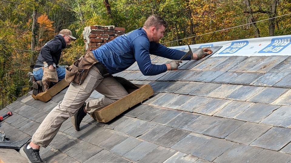 Ben Stewart, right, nails a line of Peach Bottom Slate with his father Bob who is preparing to dismantle a chimney on the Welsh immigrant cottage in Peach Bottom Township October 25, 2023. The family is a fourth generation slate roofing company based near the original slate quarries.