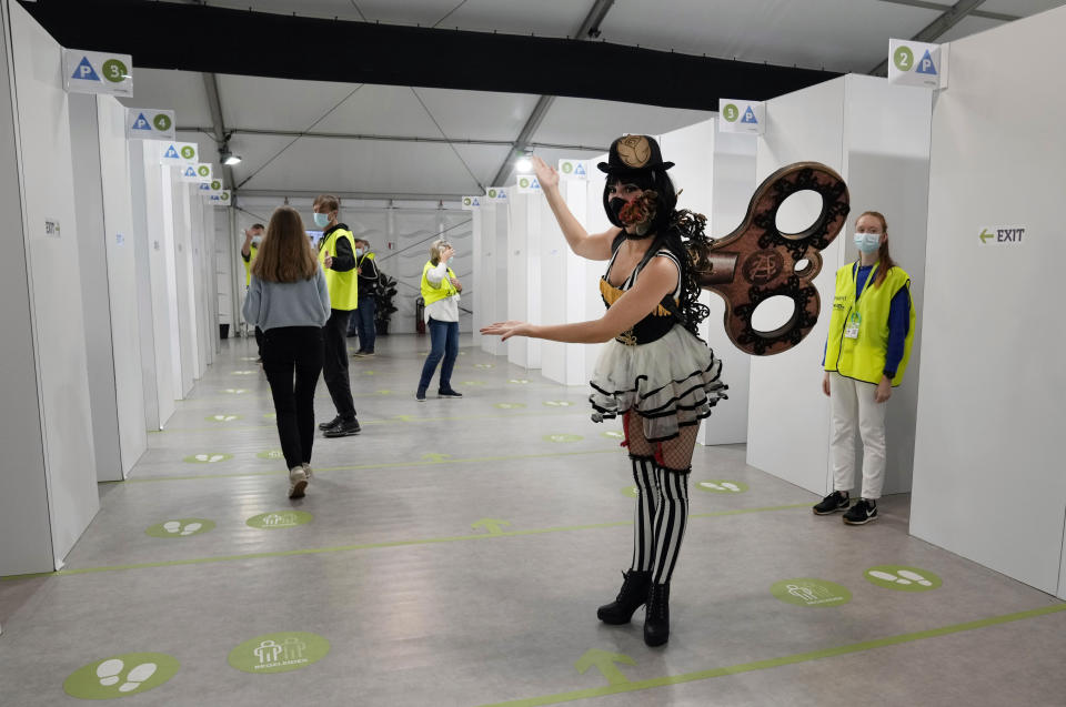 An entertainer performs as she guides people to vaccine cubicles at the Vaccine Village in Antwerp, Belgium on Wednesday, June 30, 2021. Entertainers from the popular music festival Tomorrowland performed at the Vaccine Village after the festival was cancelled this year due to COVID-19 restrictions. (AP Photo/Virginia Mayo)