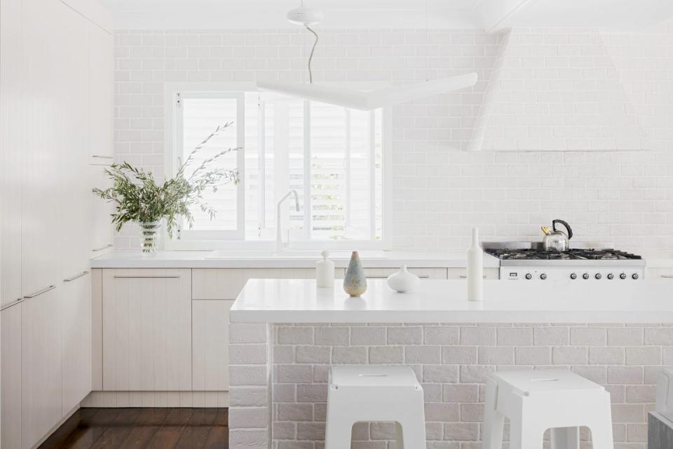 <p>Though minimalist in style, there's also a decidedly farmhouse-chic vibe going on in this kitchen by <a href="https://apdesignhouse.com.au/" rel="nofollow noopener" target="_blank" data-ylk="slk:AP Design House;elm:context_link;itc:0;sec:content-canvas" class="link ">AP Design House</a>. The brick got a fresh coat of white paint to brighten it all up and align with the rest of the surfaces and the geometric pendant asserts some modern flair. </p>