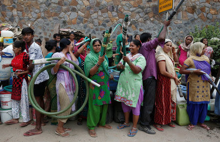 Residents hold hoses as they wait for a municipal water tanker at a colony in New Delhi, India, June 26, 2018. REUTERS/Adnan Abidi