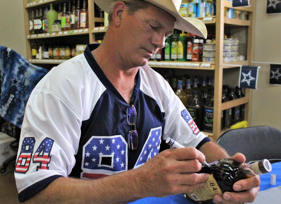 Jay Novacek, a five-time Pro Bowl tight end who first played for the St. Louis/Phoenix Cardinals and then the Dallas Cowboys, signed bottles of his new 84 Proof bourbon whiskey on July 31 at FILO Liquors. With each purchase, he signed his name and number in silver on the bottle. He also posed for photos and at 6-foot-4, he dwarfed most of his fans.