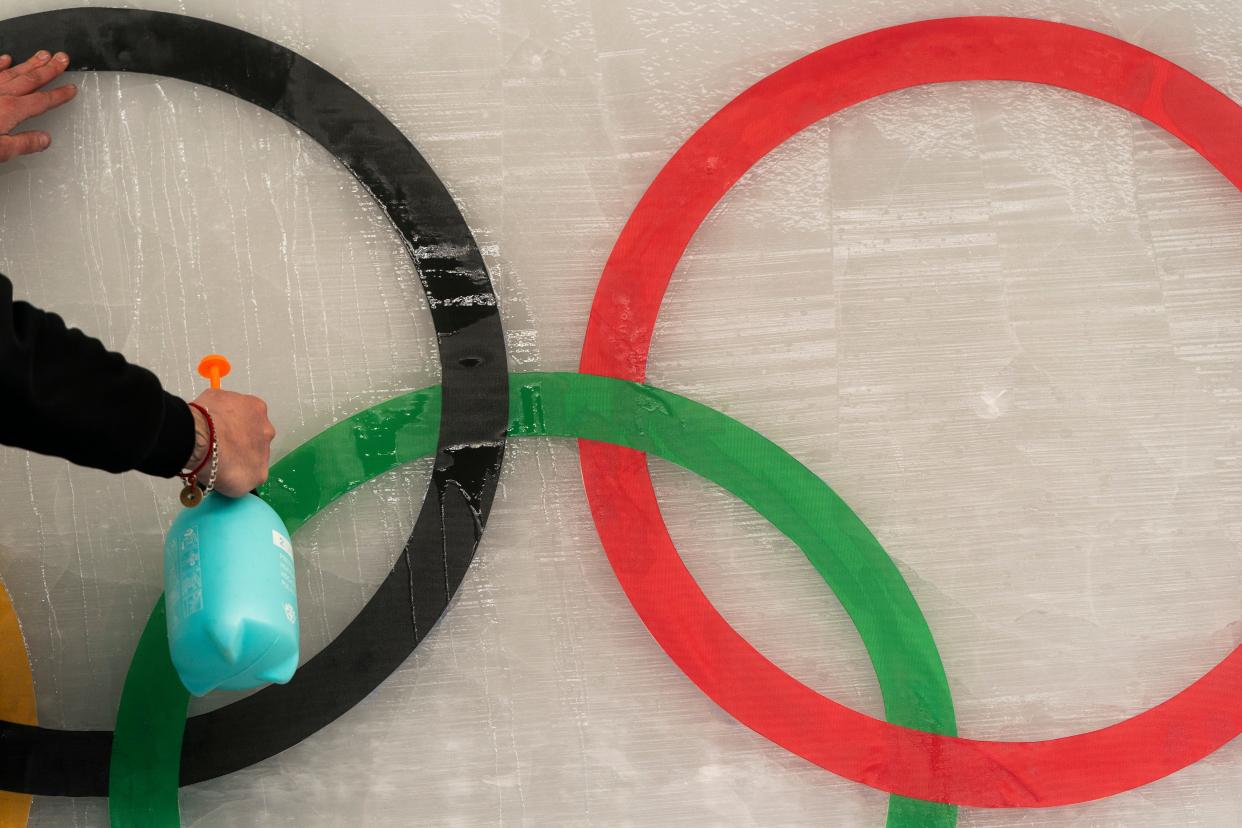 An ice maker sprays water over a cutout of the Olympic rings while installing a sub-glacial Beijing 2022 logo on the track at the Yanqing National Sliding Center ahead of the 2022 Winter Olympics, Friday, Jan. 28, 2022, in the Yanqing district of Beijing. (AP Photo/Jae C. Hong)