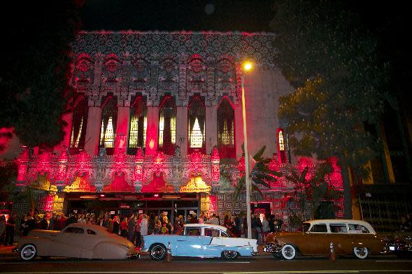 In this Wednesday, Feb. 12, 2014 photo, Lowrider cars line up outside the Mayan Theatre hosting the Lucha VaVoom Valentine’s show of Lucha Libre Mexican wrestling and Burlesque performances in Los Angeles. The esoteric hybrid of American burlesque and Mexican wrestling is an outrageous hit. (AP Photo/Damian Dovarganes)