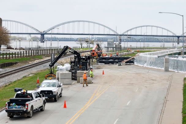 PHOTO: HESCO sand barriers are installed at right as Canadian Pacific workers, left, install barriers along River Drive and their downtown Davenport, Iowa rail line, April 24, 2023, Davenport, Iowa. (Niko Frazer/Quad City Times via AP)