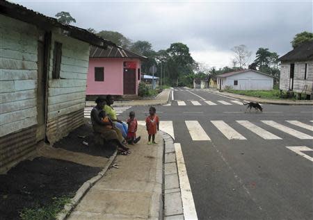 Women and children sit by the roadside in Musola February 8, 2014. REUTERS/Pascal Fletcher