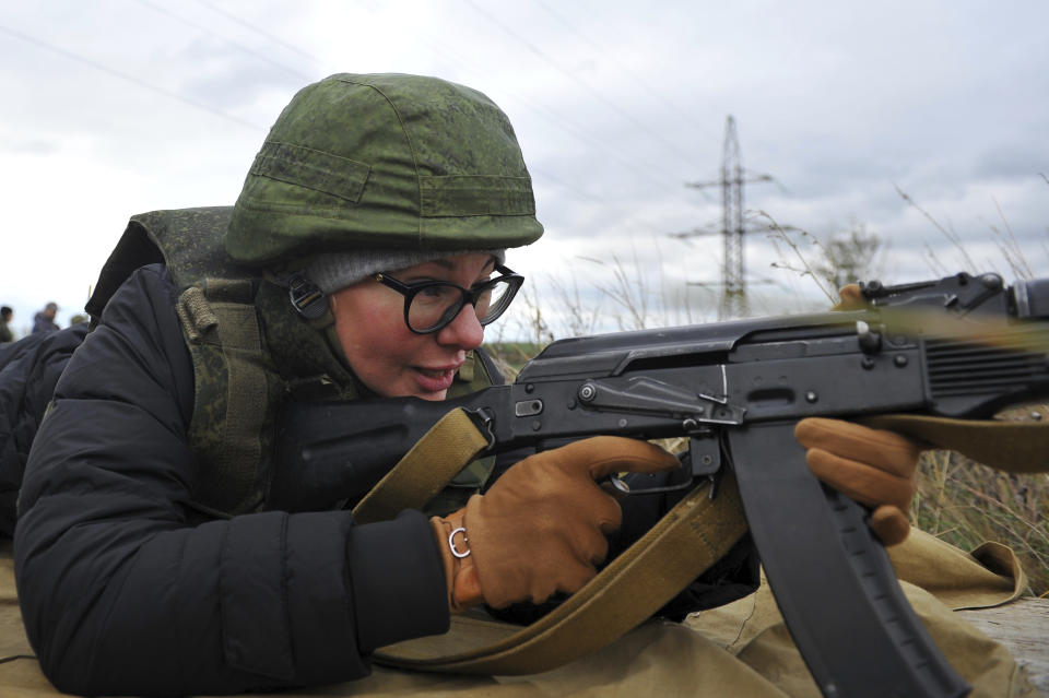 A woman prepares to fire from a Kalashnikov assault rifle at short-term courses where everyone can be able to receive military skills during theoretical and practical training is provided at a military range in Rostov-on-Don region, southern Russia, Friday, Oct. 21, 2022. (AP Photo)