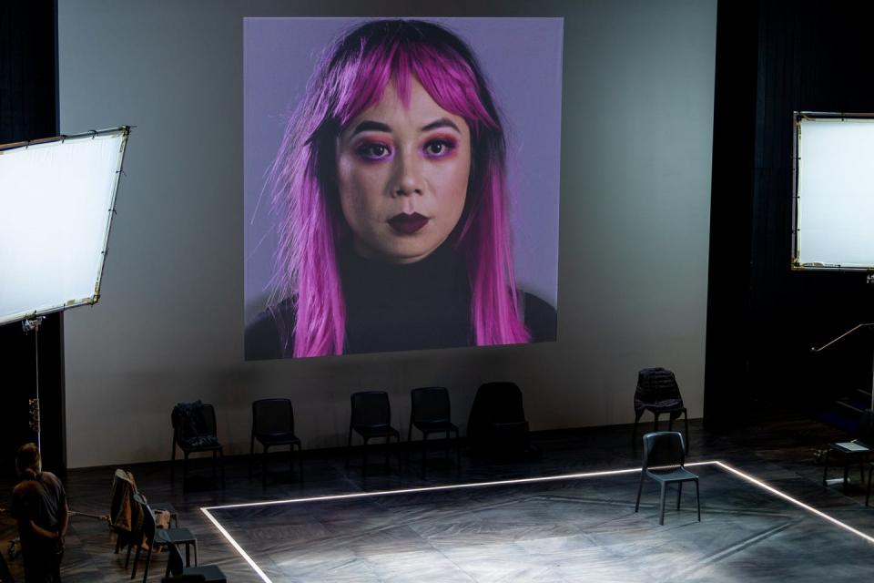 A woman stares out from a screen.