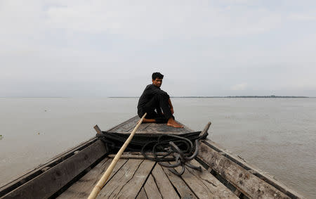 A man sits in a boat on the waters of the Brahmaputra river near the international border between India and Bangladesh in Dhubri district, in the northeastern state of Assam, India August 4, 2018. REUTERS/Adnan Abidi