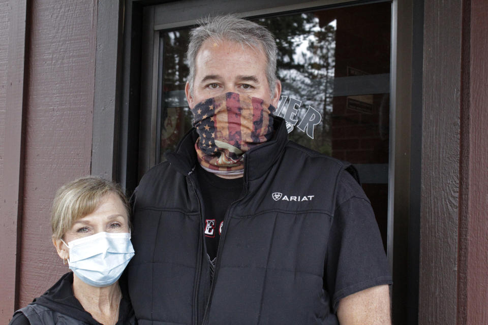 Liz and Bryan Mitchell, co-owners of the Carver Hangar, pose outside their restaurant in Boring, Ore., on Jan. 6, 2021. The restaurant is one of dozens of restaurants around the country defying state bans on indoor dining enacted due to the spread of COVID-19. In Oregon, the defiance has led to a crackdown by state regulators and thousands of dollars in fines for some establishments. (AP Photo/Gillian Flaccus)