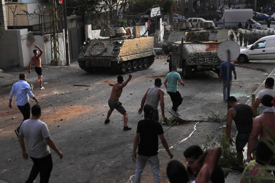 Supporters of Prime Minister-designate Saad Hariri who stepped down on Thursday, clashes with Lebanese soldiers as they throw stones against their armored personnel carriers, in Beirut, Lebanon, Thursday, July 15, 2021. Hariri says he is stepping down, nine months after he was named to the post by the parliament. He is citing "key differences" with the country's president, Michel Aoun. (AP Photo/Hussein Malla)