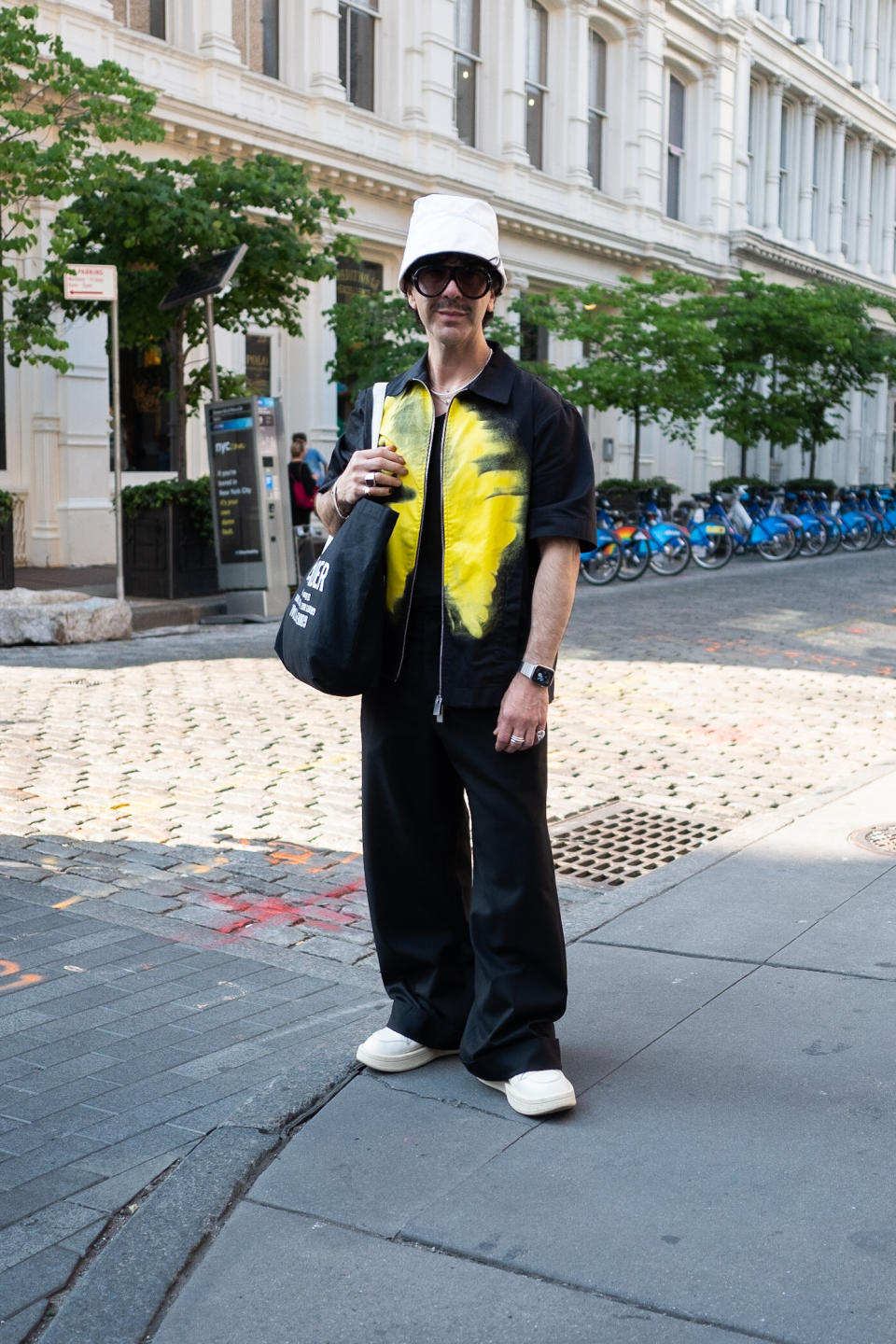 person in new york wearing cool glasses, a white hat and a yellow/black shirt