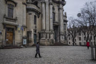 A woman walks past the Museum of the History of Religion in Lviv, western Ukraine, Friday, March 4, 2022. Workers are assembling metal containers in the patio at the museum to safely store the remaining items before placing them in basements in case the Russian invasion advances west. (AP Photo/Bernat Armangue)