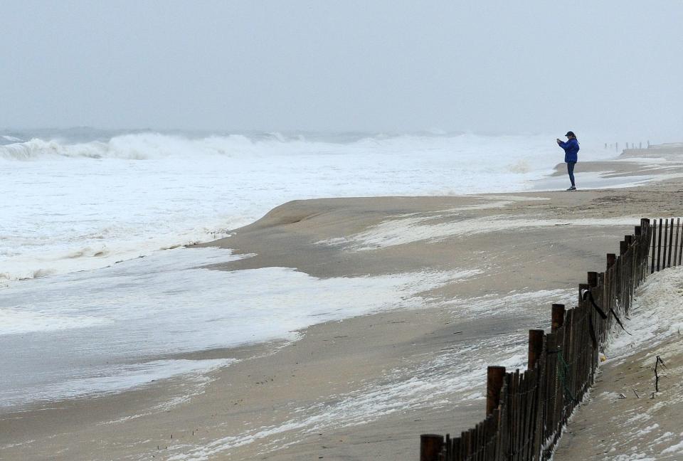 A visitor braves the winds to take a photos as a strong "Nor Easter" storm has brought some wind, rain and beach erosion with minor flooding to Rehoboth Beach and Dewey Beach on Wednesday March 21, 2018.