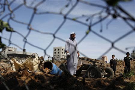 A Palestinian man inspects the scene of an Israeli air strike in the central Gaza Strip April 21, 2014. REUTERS/Ibraheem Abu Mustafa