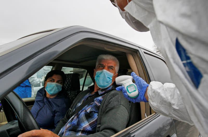 FILE PHOTO: A medical official takes the body temperature of passengers at a check point outside Bishkek