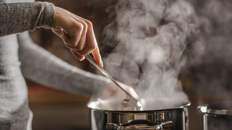 Person stirring steaming pot of soup