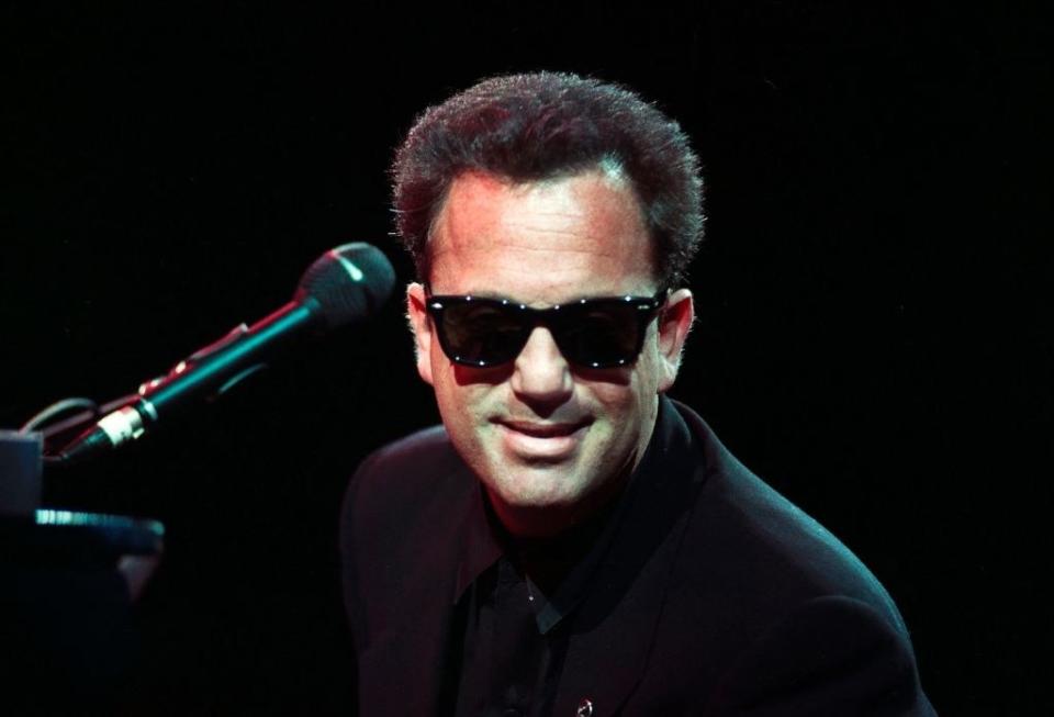 Joel in sunglasses at a microphone