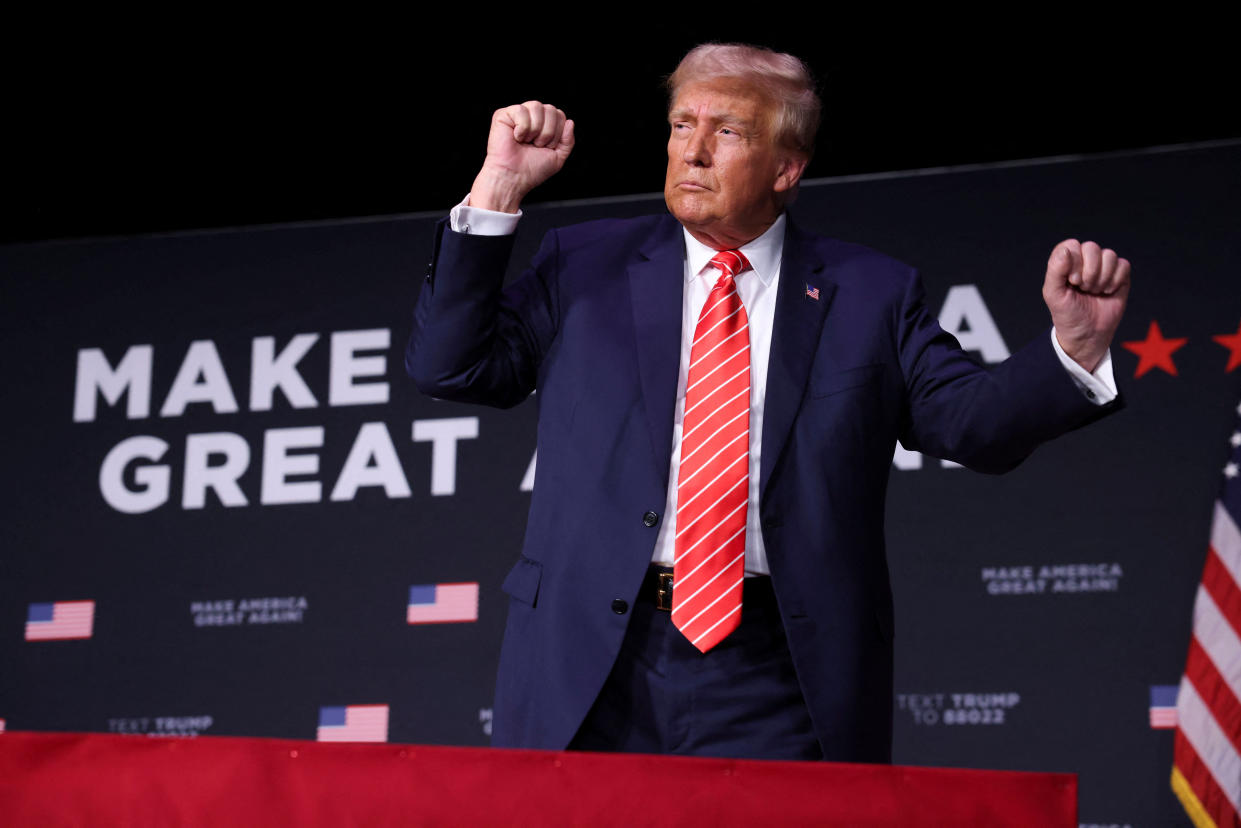 Trump holds up both fists while onstage at a rally.