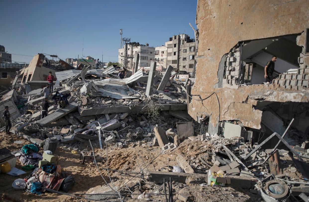 Palestinians inspect the rubble of their destroyed homes after being hit by Israeli airstrikes in the town of Beit Lahiya, northern Gaza Strip, Thursday, May 13, 2021.