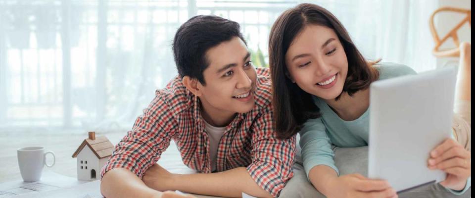 Attractive young asian adult couple looking at house plans.