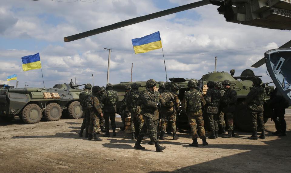 Ukrainian Army troops receive munitions at a field on the outskirts of Izyum, Eastern Ukraine, Tuesday, April 15, 2014. An Associated Press reporter saw at least 14 armored personnel carriers with Ukrainian flags, one helicopter and military trucks parked 40 kilometers (24 miles) north of the city on Tuesday. (AP Photo/Sergei Grits)