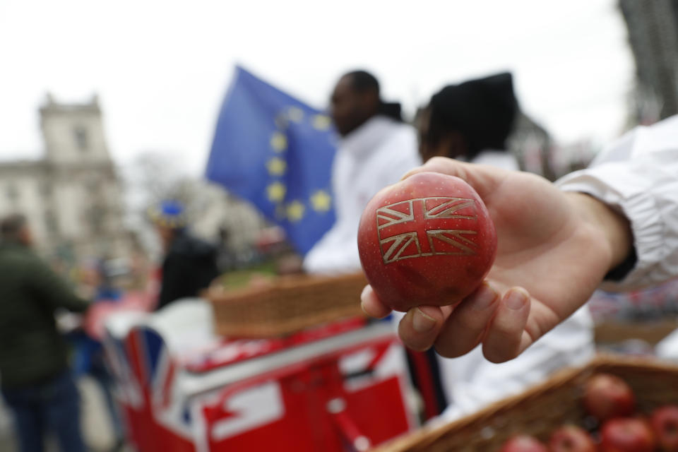A Red Viking apple with the Union Jack is given out for free to promote British produce as an Anti-Brexit demonstrator waves the European Union flag in Parliament Square