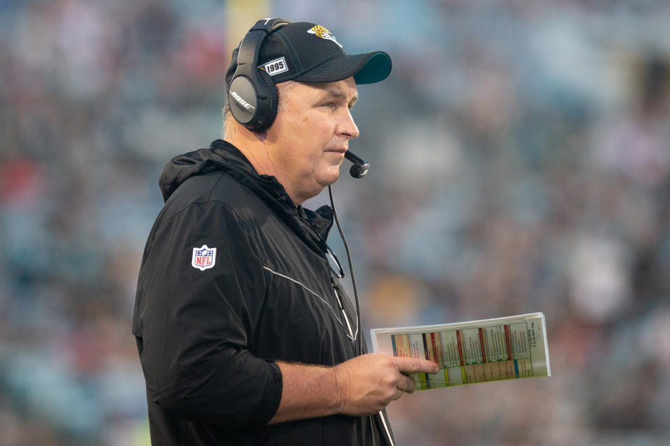 Doug Marrone holds a playcard while wearing a headset during a game.