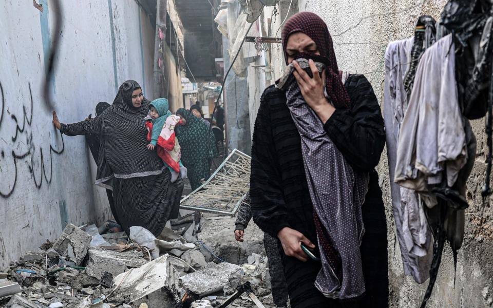 People find their way through a rubble-covered alley, following overnight Israeli bombardment in Rafah in the southern Gaza Strip on February 25, 2024, amid continuing battles between Israel and Hamas.