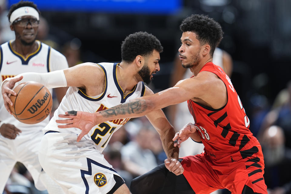 Denver Nuggets guard Jamal Murray, front left, struggles to control the ball as Portland Trail Blazers forward Toumani Camara, right, defends in the first half of an NBA basketball game Sunday, Feb. 4, 2024, in Denver. (AP Photo/David Zalubowski)