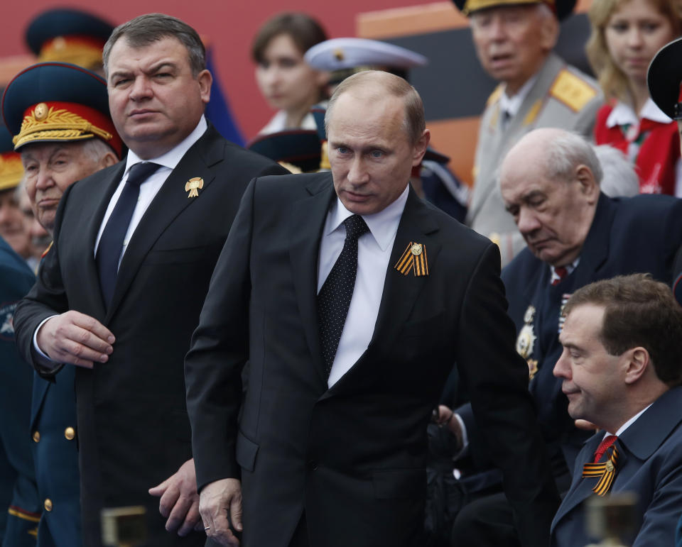 FILE - In this Wednesday, May 9, 2012 file photo, Russia's Defense Minister Anatoly Serdyukov, left, Russian President Vladimir Putin, center, and Prime Minister Dmitry Medvedev, bottom right, watch the Victory Day Parade, in Moscow. Russian President Vladimir Putin has fired the country's defense minister two weeks after a criminal probe was opened into alleged fraud in the sell-off of military assets. Putin made the announcement of Anatoly Serdyukov's dismissal on Tuesday Nov. 6, 2012 in a meeting with Moscow regional governor Sergei Shoigu, whom he appointed as the new minister. (AP Photo/Alexander Zemlianichenko)