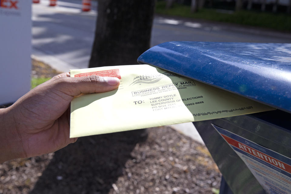 FILE - Miami-Dade resident James Curity deposits a ballot in a U.S. Postal Service mail box outside City Hall during early voting for the general election, Wednesday, Oct. 28, 2020, in Miami Beach, Fla. On Friday, Oct. 28, 2022, The Associated Press reported on stories circulating online incorrectly claiming absentee ballots will not be accepted unless voters mail them with up to two stamps. (David Santiago/Miami Herald via AP, File)