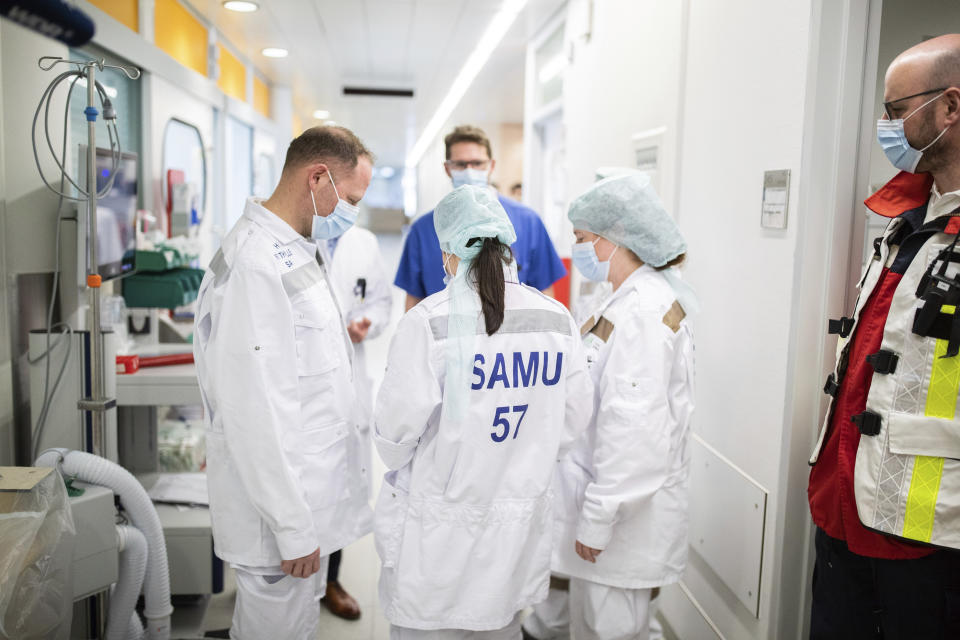 Doctors from France discuss in front of room where a COVID-19 patient from France is being treated at the University Hospital in Essen, Germany, Wednesday, April 1, 2020. Today patients infected with the coronavirus and seriously ill with Covid-19 were flown from France to Essen. For most people, the new coronavirus causes only mild or moderate symptoms, such as fever and cough. For some, especially older adults and people with existing health problems, it can cause more severe illness, including pneumonia. (Marcel Kusch/dpa via AP)