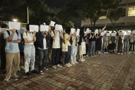 Protesters hold up blank white papers during a commemoration for victims of a recent Urumqi deadly fire at the Chinese University of Hong Kong in Hong Kong, Monday, Nov. 28, 2022. Students in Hong Kong chanted “oppose dictatorship” in a protest against China’s anti-virus controls after crowds in mainland cities called for President Xi Jinping to resign in the biggest show of opposition to the ruling Communist Party in decades. (AP Photo/Kanis Leung)