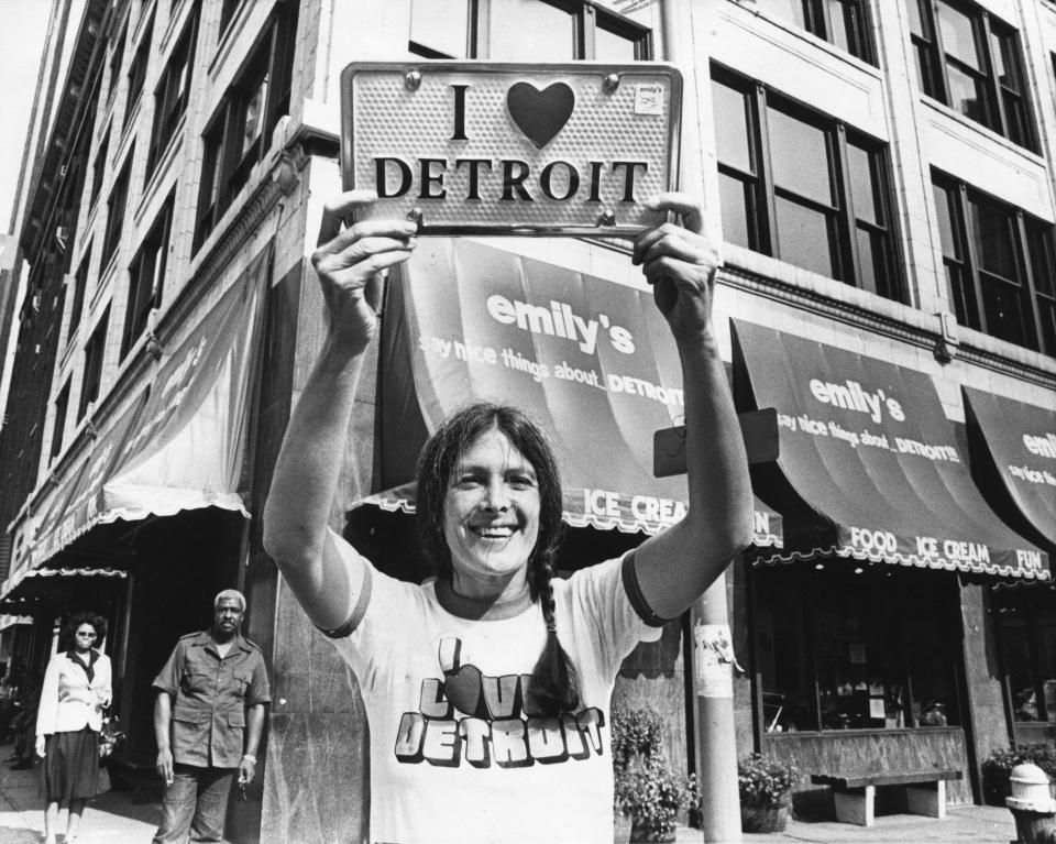 Emily Gail holding up a license plate in 1981 outside her shop in Detroit.