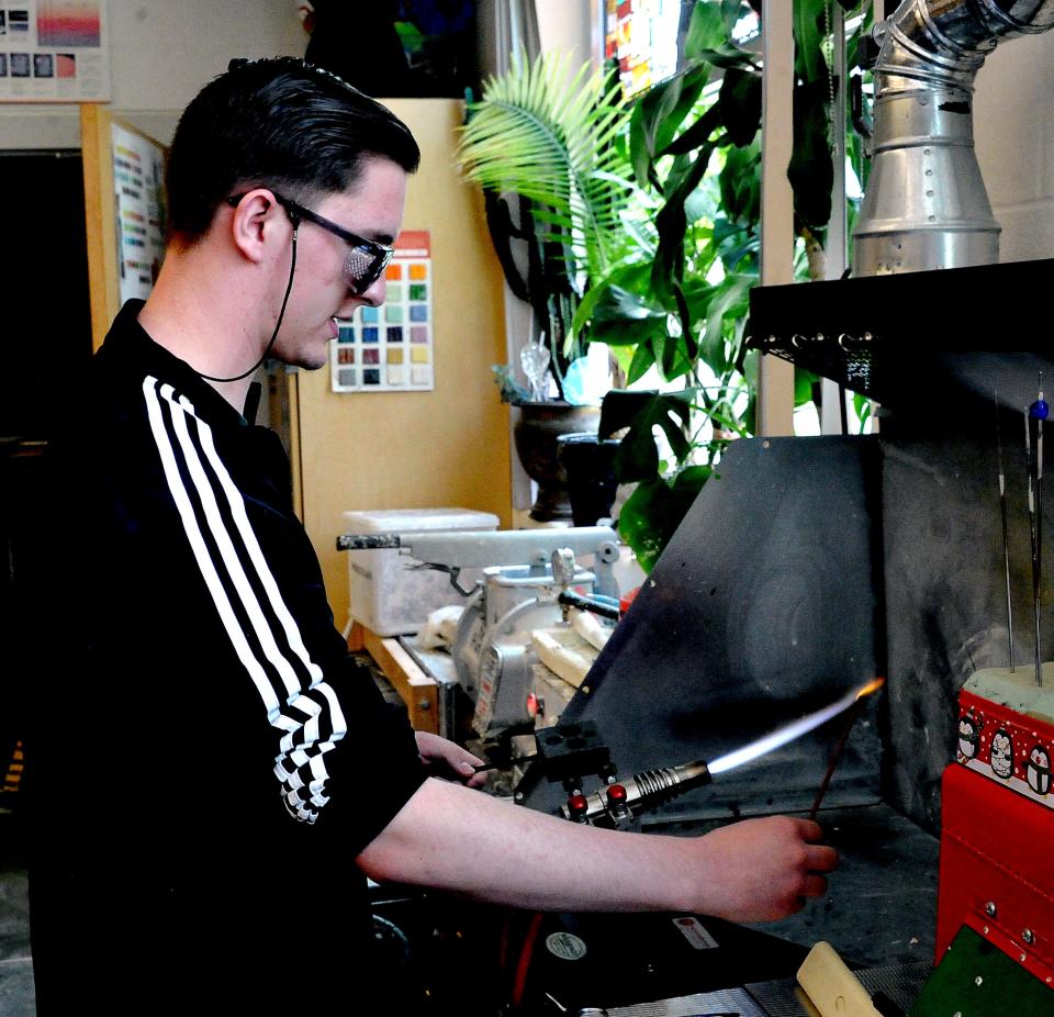 Josh Smucker heats a glass rod to make a mushroom using Smithville High School's glassblowing torch.