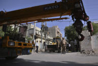 Pakistan army soldiers stand beside the heavy machinery park on a street leading to the site of a plane crash, in Karachi, Pakistan, Sunday, May 24, 2020. A passenger plane belonging to state-run Pakistan International Airlines carrying passengers and crew crashed Friday near the southern port city of Karachi. (AP Photo/Fareed Khan)