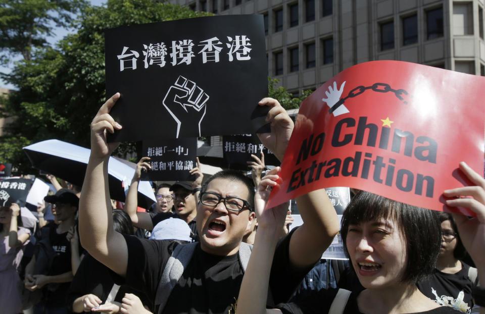 FILE - In this June 16, 2019, file photo, Hong Kong students and Taiwan supporters hold up cards which read "Taiwan Support Hong Kong" and "No China Extradition" to support Hong Kong protesters against an extradition law outside of the Legislative Yuan in Taipei, Taiwan. Recent anti-government protests in Hong Kong are echoing in Taiwan, possibly giving the island's President Tsai Ing-wen a lift in her campaign to resist Beijing's pressure for political unification and win a second term in next year's elections. (AP Photo/Chiang Ying-ying, File)